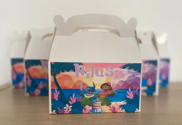 Boîtes à lunch personnalisées avec le thème 'Nilusi' et des personnages de Lilo et Stitch, disposées en ligne sur une surface en bois.