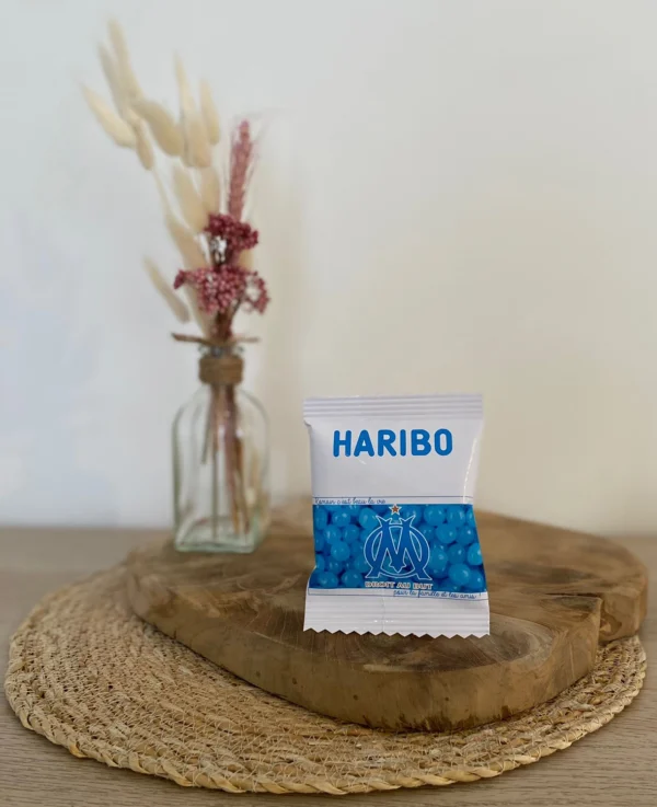 Sachet Haribo personnalisé avec le logo de l'OM, posé sur un support en bois.